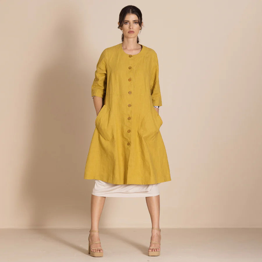 Woman wearing a mustard yellow dress with a plain background