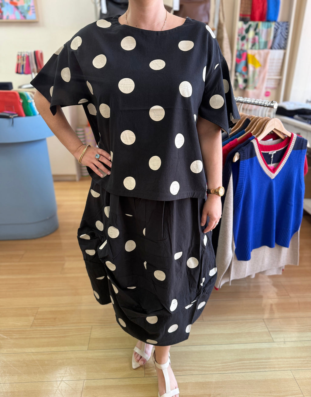 Person wearing a black outfit with white polka dots in a store setting